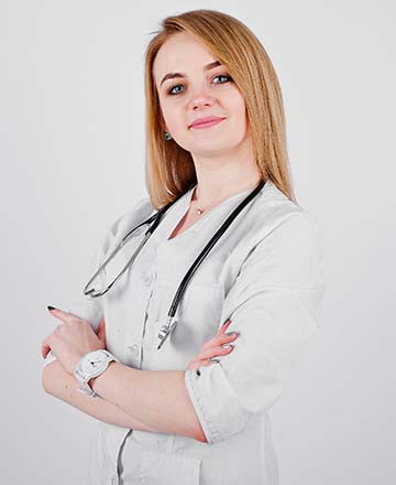 Женщина врач в белом халате смотрит в камеру